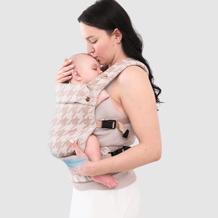 Mutter trägt ihr Baby vorne in der beigekarierten Dane Babytrage