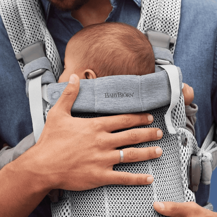 Vielreisende Mutter am Flughafen trägt Baby vor dem Bauch in beiger Erd Premium