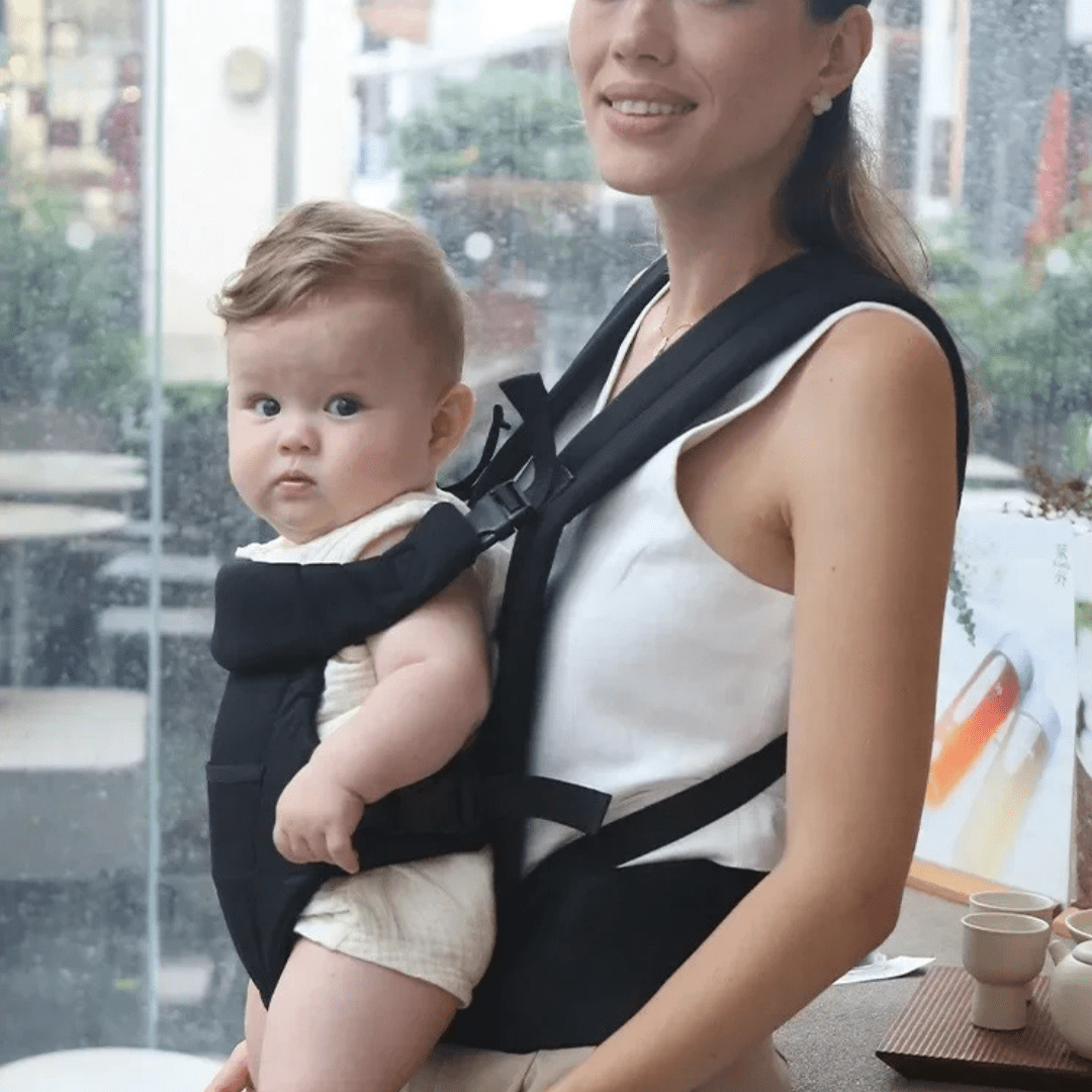 Mutter trägt ihr Baby in der grauen Lacey Babytrage beim Stadtbummel