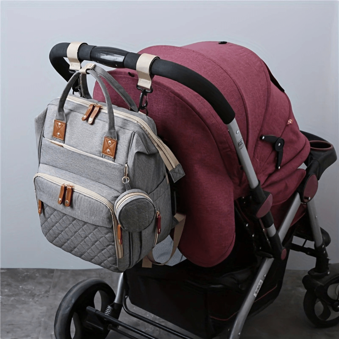 grauer wickelrucksack am kinderwagen befestigt