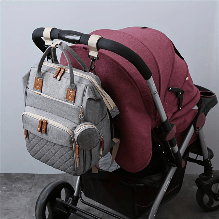grauer wickelrucksack am kinderwagen befestigt