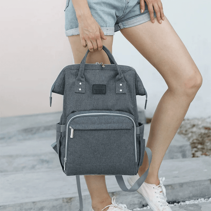 frau haelt grauen wickelrucksack am strand