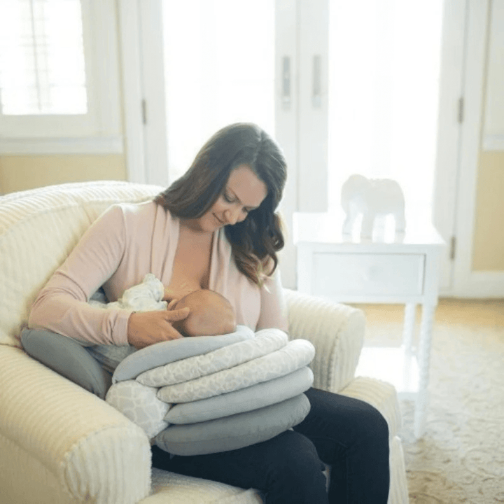 Mutter stillt ihr Baby entspannt auf dem Sofa mit aufgeklapptem Teagan Stillkissen
