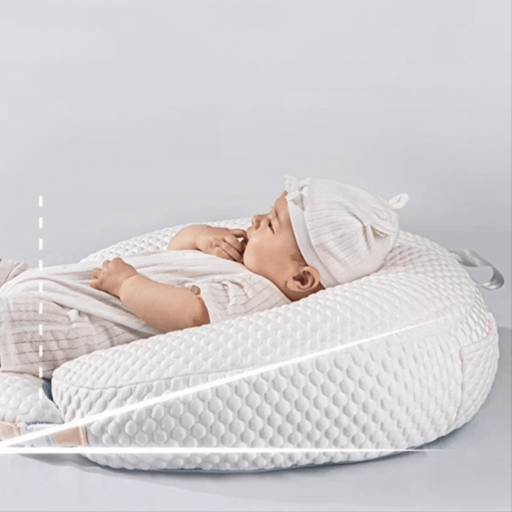 Baby schläft sicher auf weißem Willow Stillkissen in einem Stubenwagen
